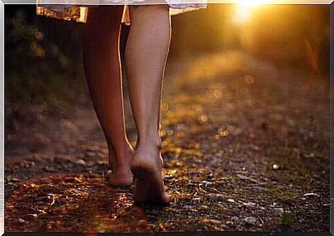 A woman walks barefoot in a forest