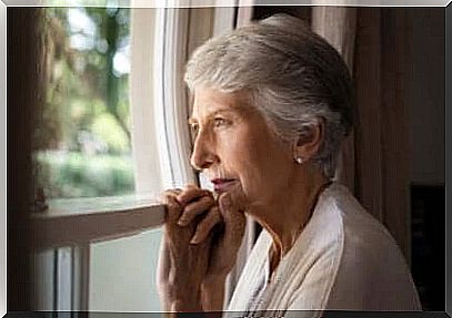 An elderly woman looks out the window