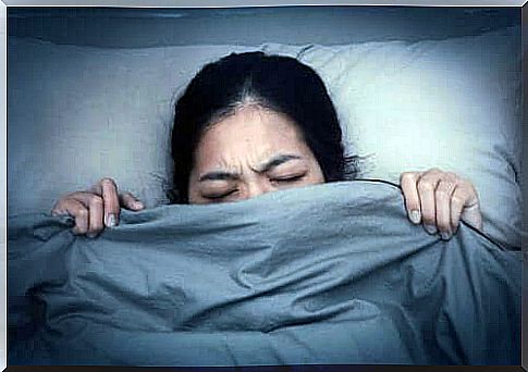 A woman pulls the blanket up to her chin