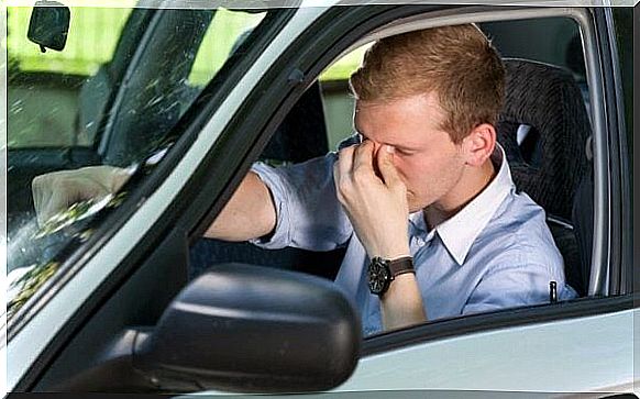 Man rubs his eyes behind the wheel of his car