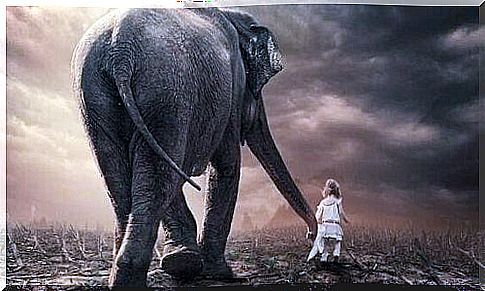 Little girl holding an elephant's trunk and walking with him through a withered landscape